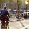 Man in pak fietst naar werk in binnenstad Amsterdam