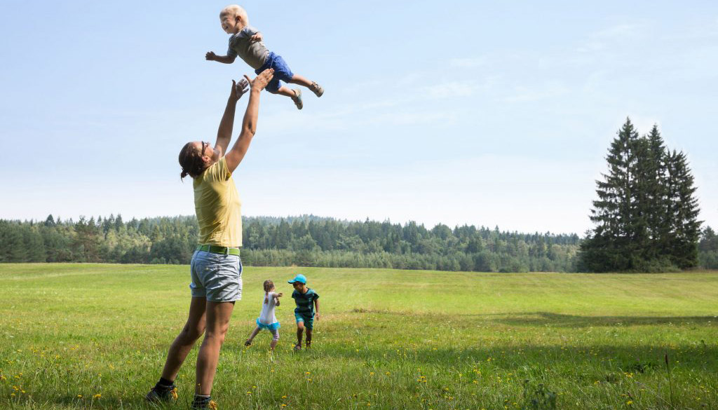 Man houdt kind in de lucht in landschap