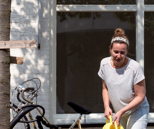 Vrouw geeft planten water in geveltuin in straat in Utrecht