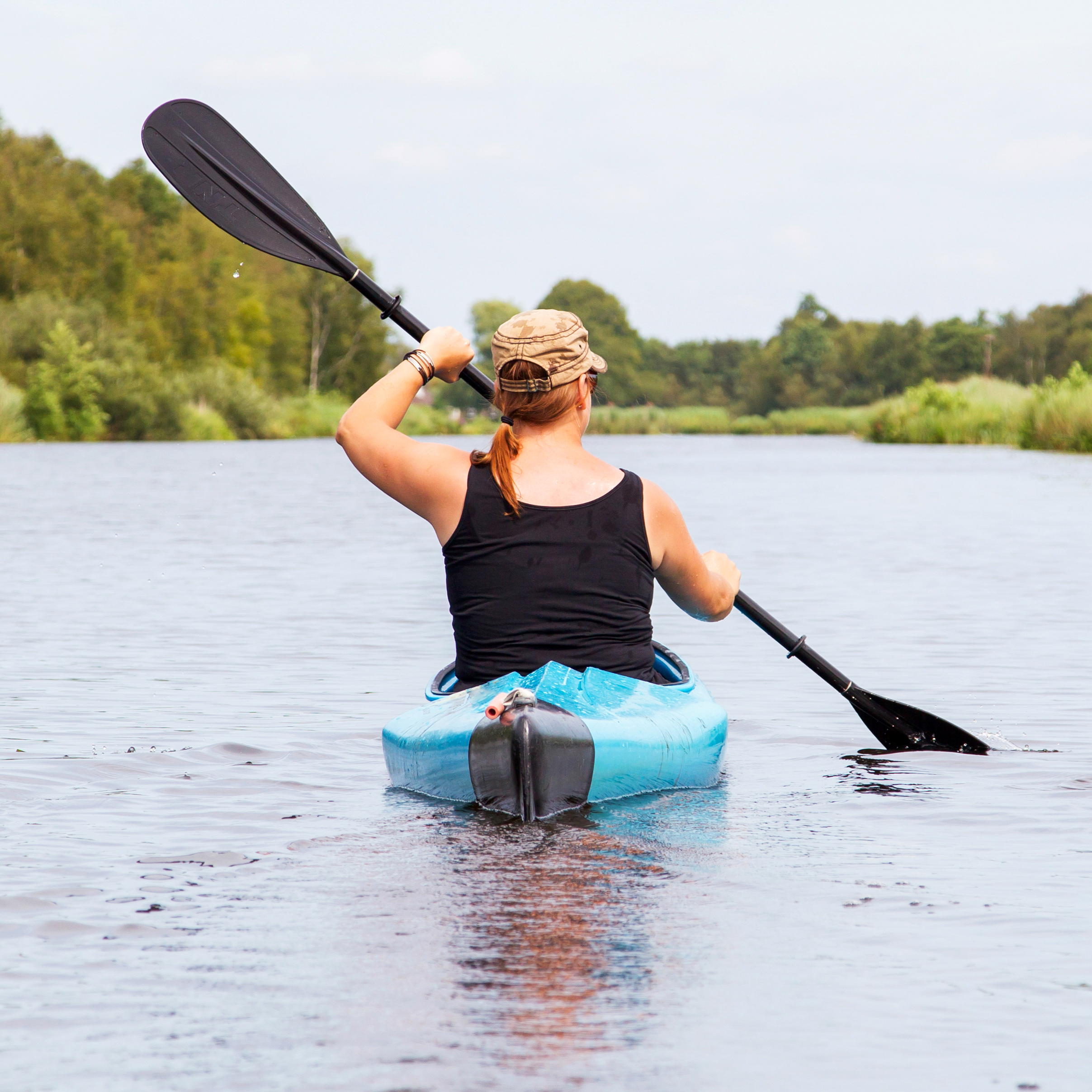 Vrouw in een blauwe kayak op het water
