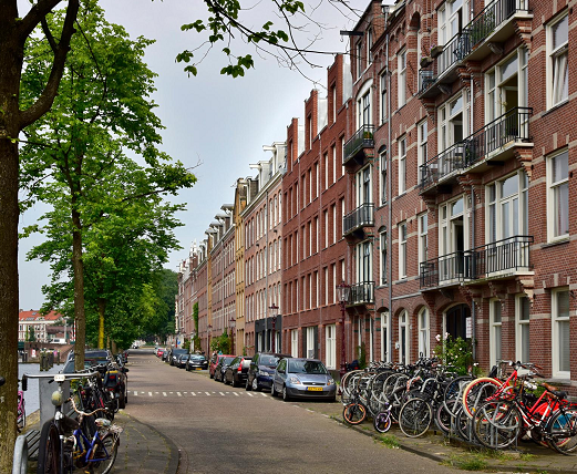 Een straat langs de gracht, het ziet er krap uit met geparkeerde auto's tussen de straat en de stoep