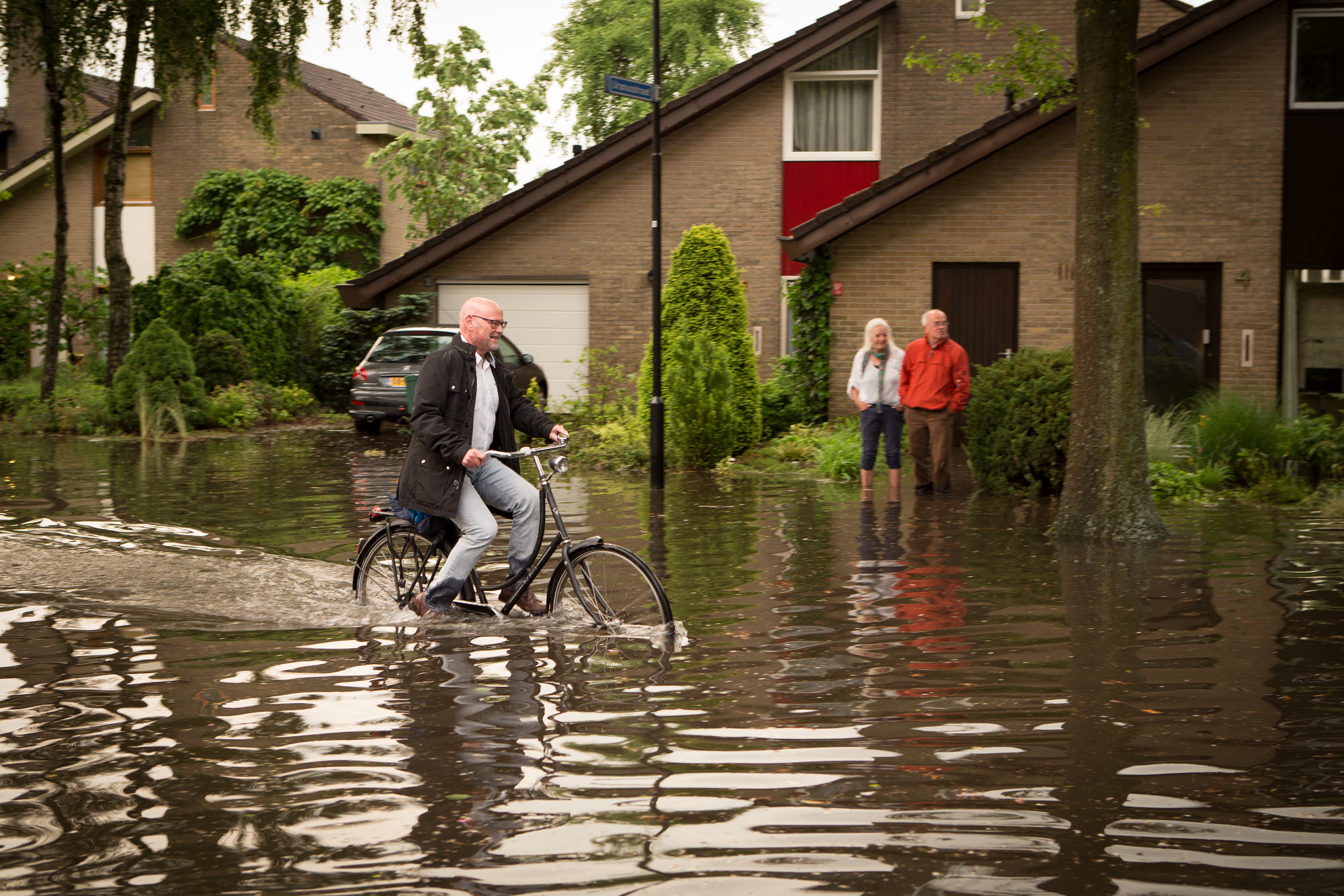 Fietser rijdt door ondergelopen straat