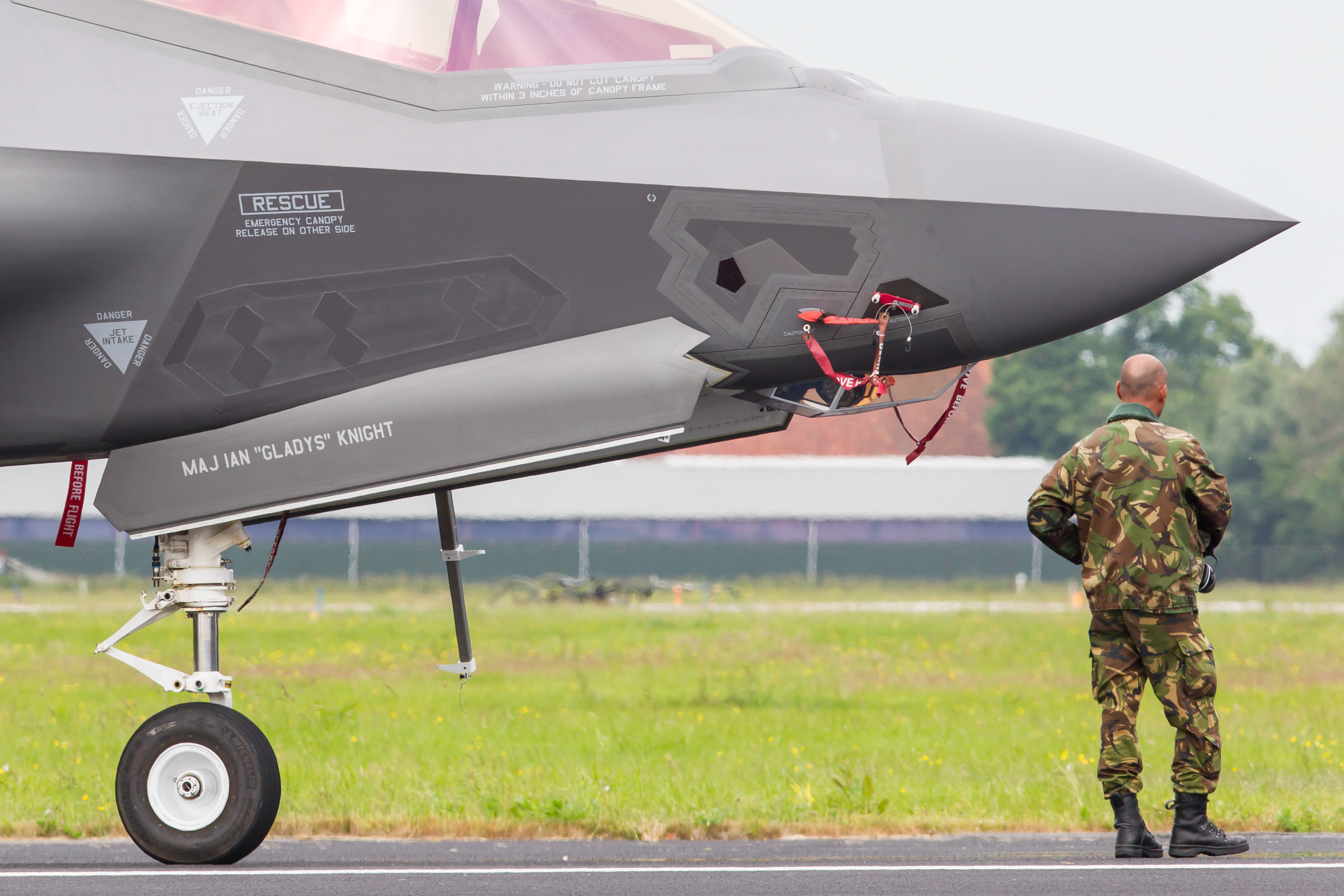man in camouflage outfit naast de neus van een straaljager