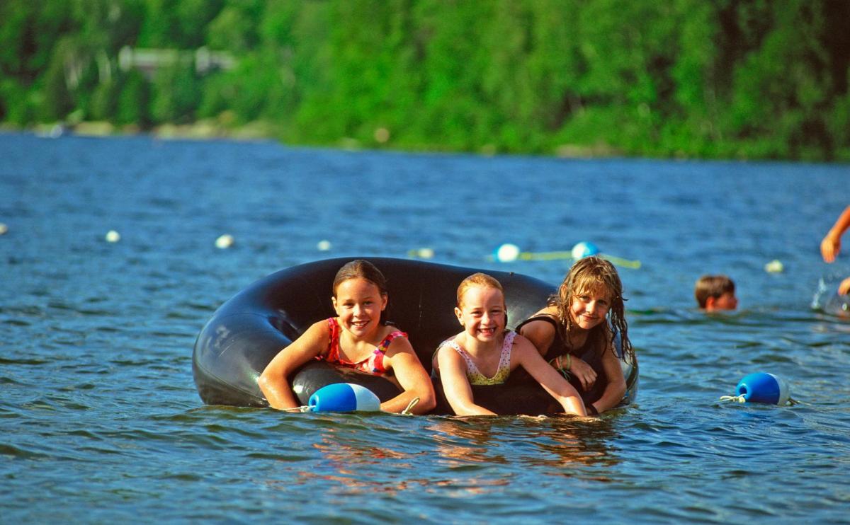 Een foto van drie kinderen op een grote opblaasband in een meer