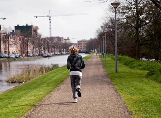 Vrouw jogt over wandelpad langs water