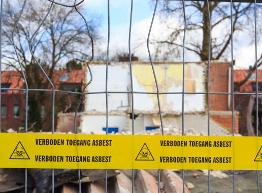Hek  voor huizen met daarop lint met tekst verboden toegang asbest