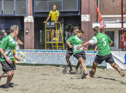Beachvoetbal op strand, scheidsrechter kijkt toe