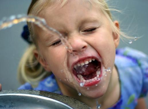 Kind drinkt water uit een fonteintje