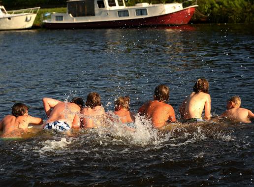 zwemmende kinderen hangend over een surfplank