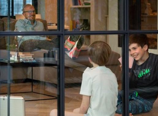 Foto van een vader met twee kinderen in de woonkamer