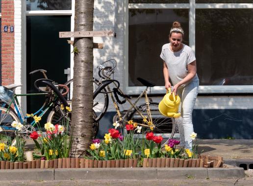 Vrouw geeft planten in geveltuin water in straat in Utrecht