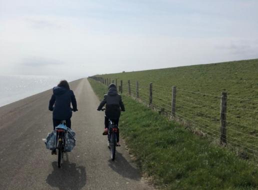 Dieneke fiets samen met haar zoontje over een weg langs de kust