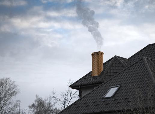 een schoorsteen op een huis waar rook uit komt