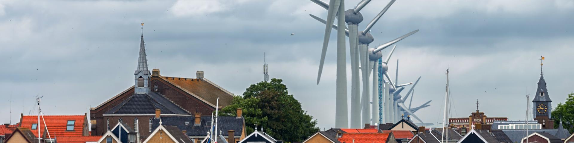 Een rij windturbines die vlakbij huizen staan