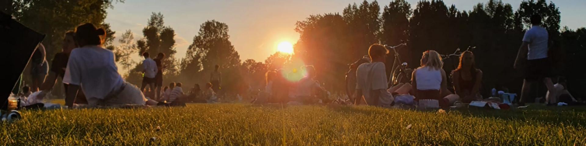 Jonge mensen zitten in een park bij zonsondergang