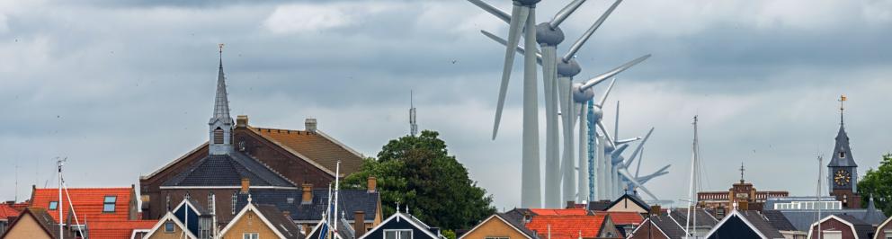 Een rij windturbines die vlakbij huizen staan