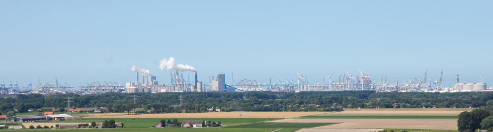 panoramafoto met blauwe lucht, industrie met rook, woningen en groen