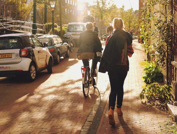 Fietsers, wandelaars en geparkeerde auto's in straat in Leiden in schemering