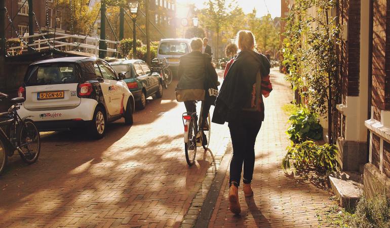 Fietsers, wandelaars en geparkeerde auto's in straat in Leiden in schemering