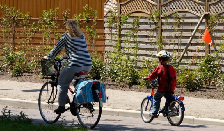 Moeder en kind op de fiets door een straat in een woonwijk