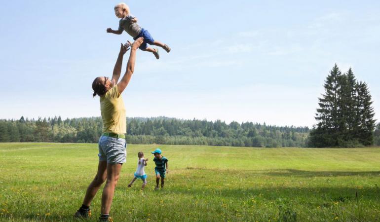 Man houdt kind in de lucht in landschap