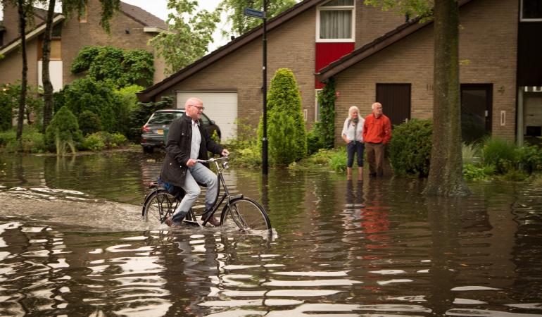 wateroverlast - man fiets door onder gelopen straat