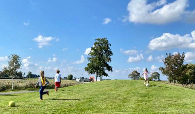 Drie kinderen spelen op een grasveld met een bal