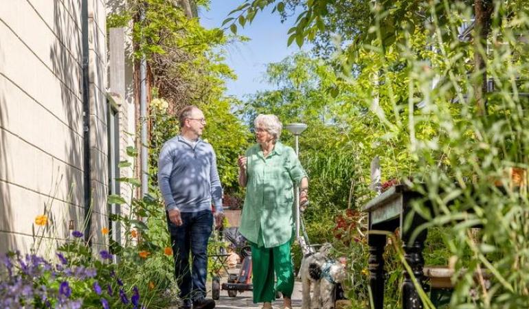 Man en vrouw laten hond uit tussen het groen in de stad
