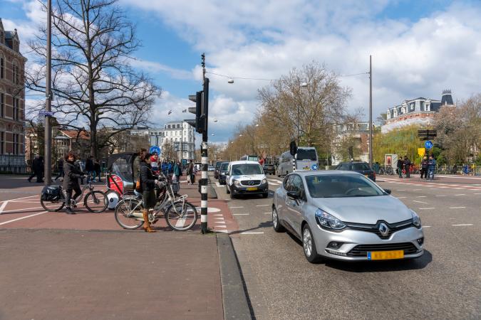 fietsers wachten links voor een stoplicht, auto's rijden rechts