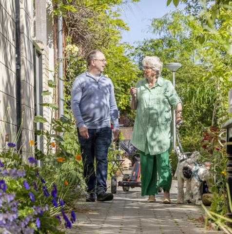 Man en vrouw wandelen met hond in groene stad