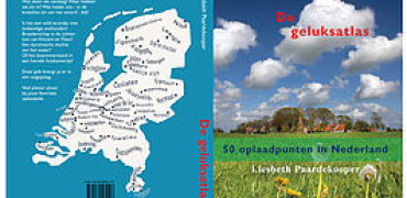 Voor- en achterkant van het boek Geluksatlas met een foto van Nederland op de achterkant en een foto van gras met bebouwing en wolken op de voorkant