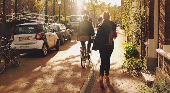 Fietsers, wandelaars en geparkeerde auto's in straat in Leiden in schemering