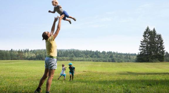Man houdt kind in de lucht in landschap