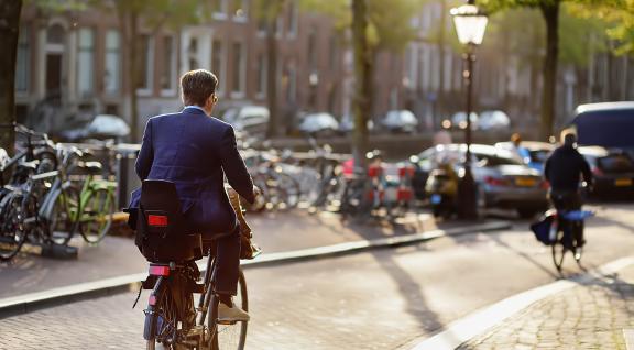 Man in pak fietst naar werk in binnenstad Amsterdam
