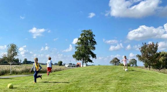 Drie kinderen spelen op een grasveld met een bal