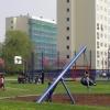 Kinderen spelen in een speeltuin met op de achtergrond een flat