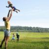 Man houdt kind in de lucht in landschap