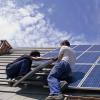 Twee installateurs plaatsen zonnepanelen op een dak tijdens zonnig weer