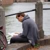 Man leest boek aan gracht